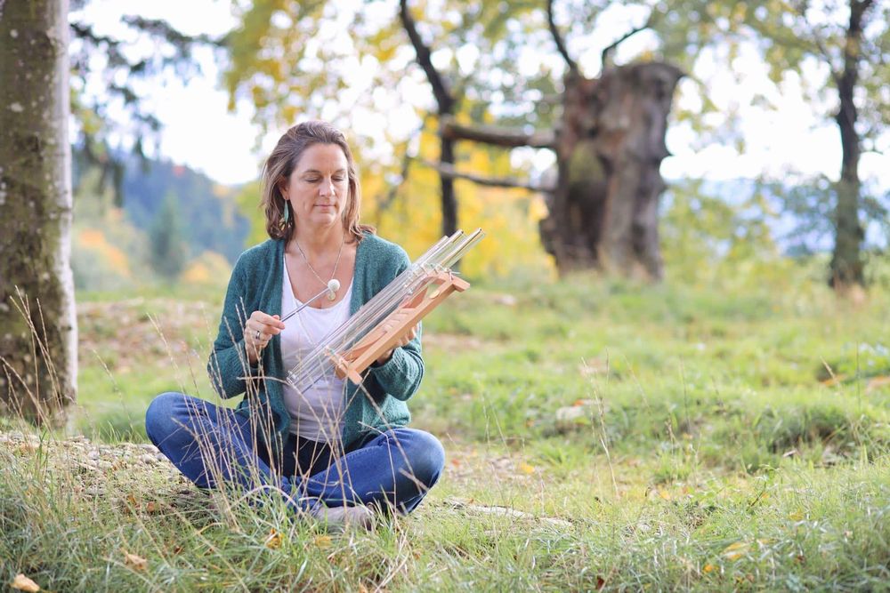 Anke Braun sitzt im Gras, vor sich einen Holzrahmen