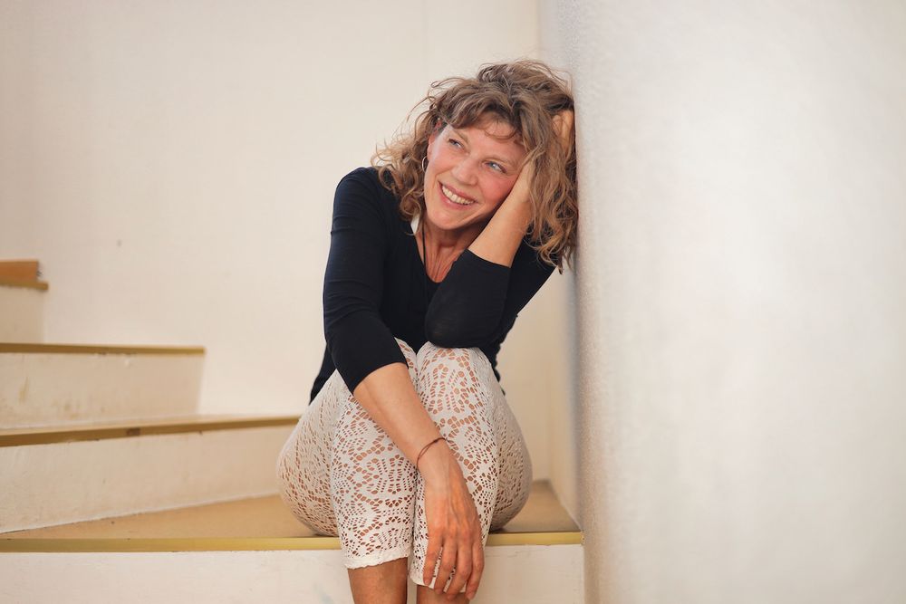 Susanne End sitzt auf einer Treppenstufe und lehnt den Kopf an die Hand
