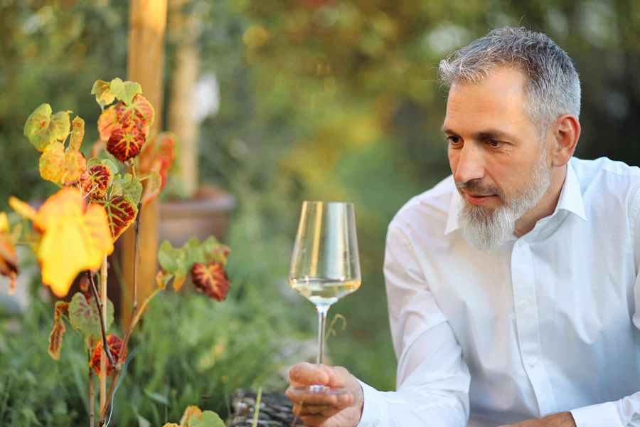 Laurent Mueller mit einem Weinglas zwischen Herbstblättern